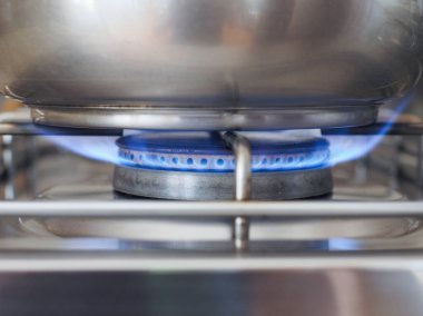 Çelik tencere mavi gaz alevi ile ocağın üstünde