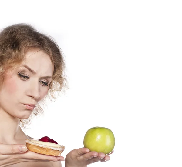 Junge, fröhliche Frau, die sich zwischen Apfel und Kuchen entscheidet — Stockfoto