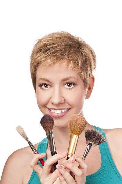 Positieve blond in studio met make up borstels — Stockfoto