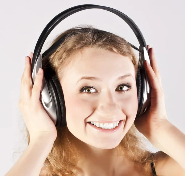 Menina com fones de ouvido no fundo cinza — Fotografia de Stock