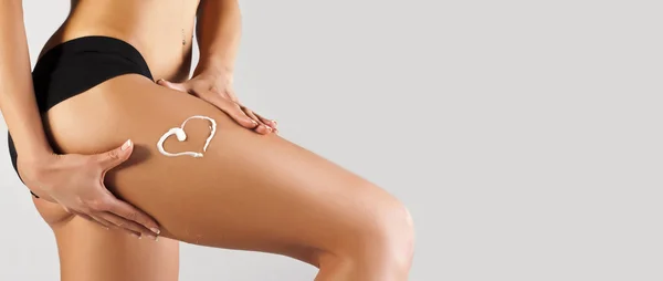 Femme appliquant crème hydratante sur les jambes — Photo