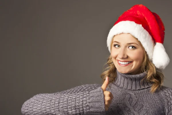 Feliz chica sonriente en sombrero de santa mostrando los pulgares hacia arriba — Foto de Stock