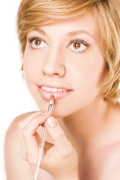 Женщина наносит макияж на губы кистью — стоковое фото