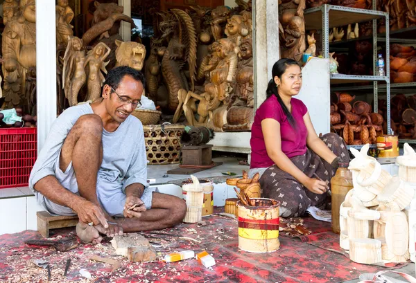A man and a woman are making wooden crafts