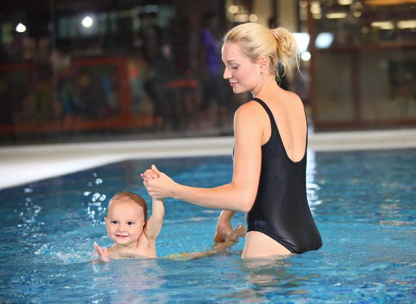 Joven madre alegre e hijo pequeño en una piscina — Foto de Stock