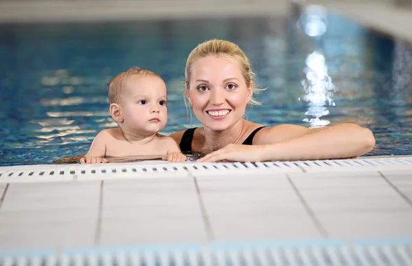 Jovem mãe alegre e pequeno filho em uma piscina — Fotografia de Stock