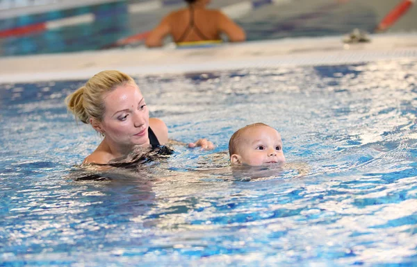 Joven madre e hijo pequeño en una piscina — Foto de Stock