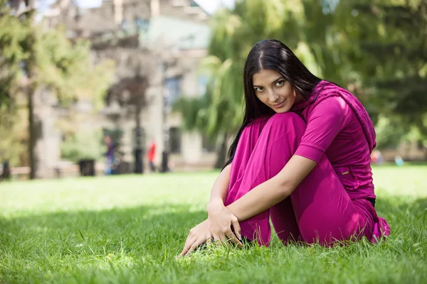 Jeune fille assise sur l'herbe dans le parc — Photo