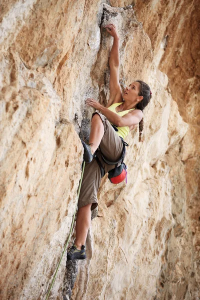 Νεαρή γυναίκα ροκ ορειβάτης για ένα πρόσωπο απότομων βράχων — Φωτογραφία Αρχείου