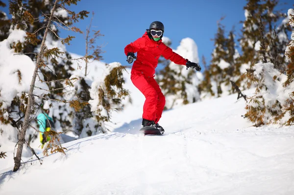 Female snowboarder going to jump on mountain slope — Stock Photo, Image