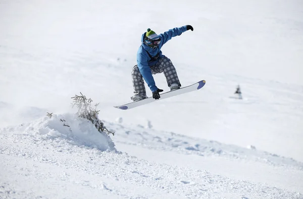 Junger männlicher Snowboarder springt auf schneebedecktem Hang — Stockfoto