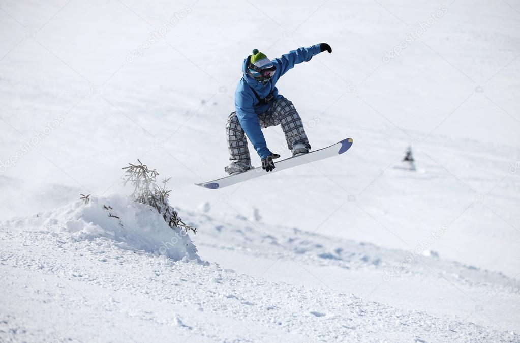 Young male snowboarder jumping on a snowy slope