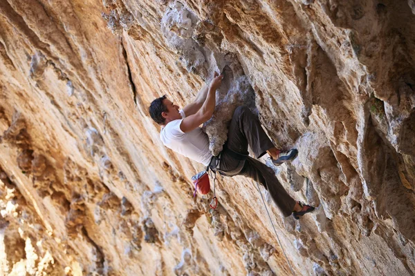 Rock climber struggling to take next handhold — Stock Photo, Image