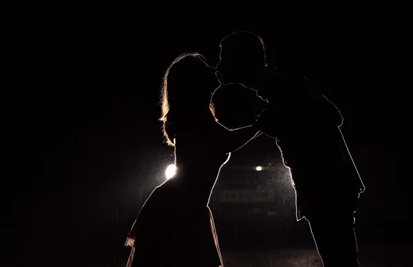 Silhouette of a young couple in the dark against car headlights — Stock Photo, Image