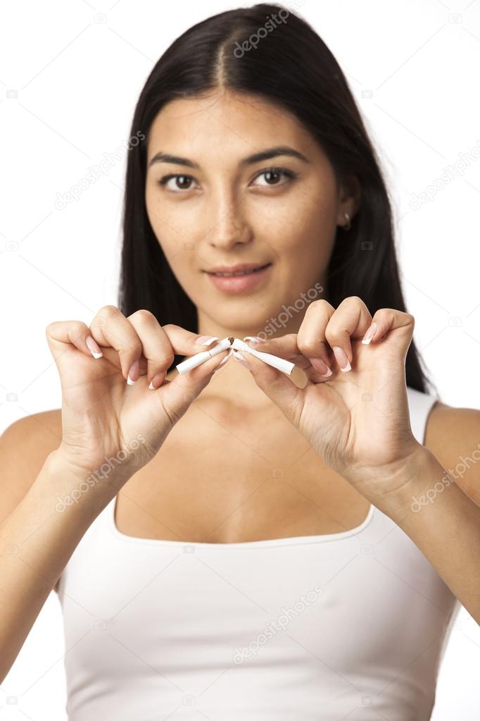 Closeup of a young woman breaking a cigarette while isolated on a white background