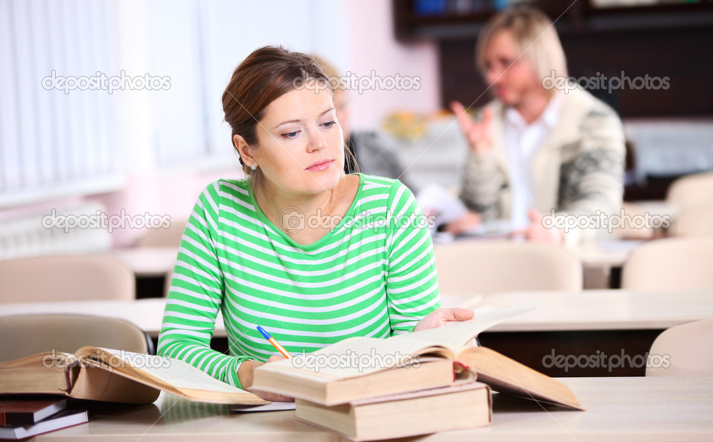 Young woman studying at desk with lots of books