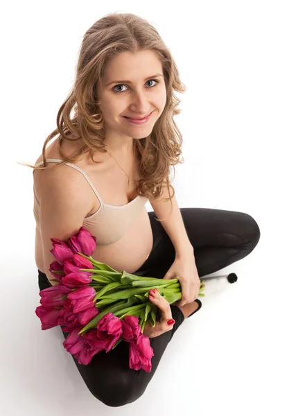 Happy young pregnant woman holding flowers — Stock Photo, Image