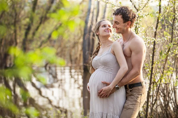 Jonge zwangere paar aan de rivier in het voorjaar van — Stockfoto