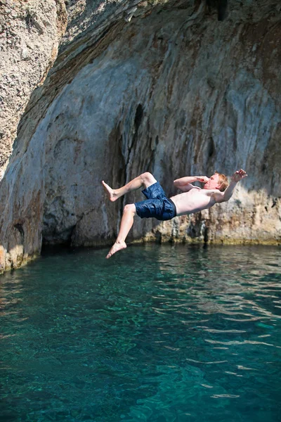 Deep water soloing, young male rock climber jumping from a cliff — Stock Photo, Image
