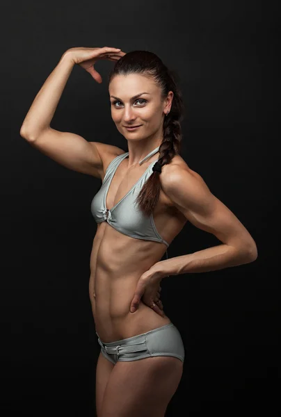 Young fitness woman in bikini flexing bicep — Stock Photo, Image