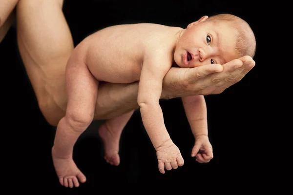 Pequeño bebé en padres mano sobre fondo negro — Foto de Stock