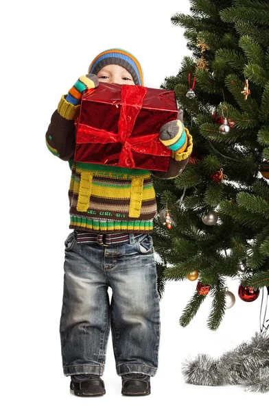 Cute little boy with gift near Christmas tree — Stock Photo, Image