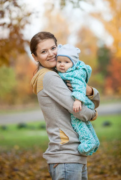 Ung kvinna och hennes baby son i höst park — Stockfoto