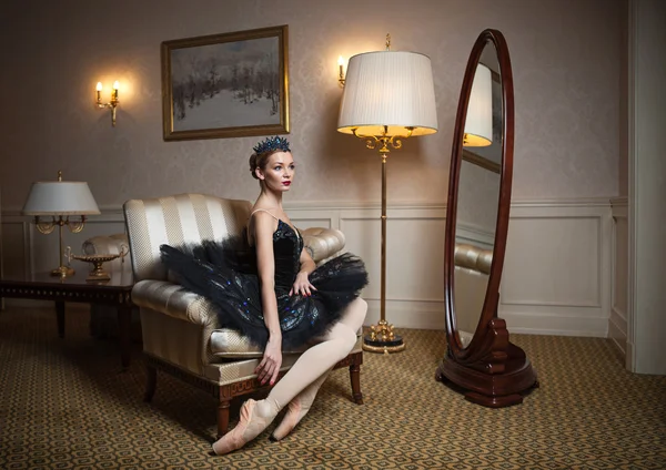 Ballerina in black tutu sitting in armchair