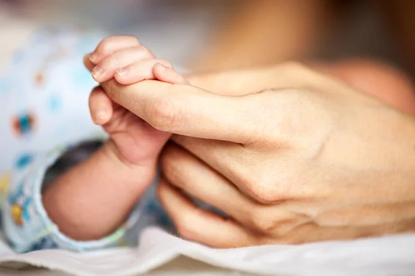 Yeni doğmuş bebek annesinin elini tutuyor. — Stok fotoğraf