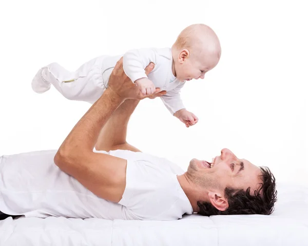 Jeune homme tenant bébé fils tout en étant couché sur le dos — Photo
