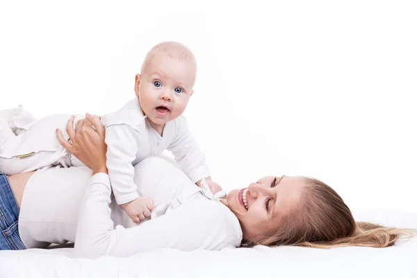 Young woman holding baby son while lying on back — Stock Photo, Image