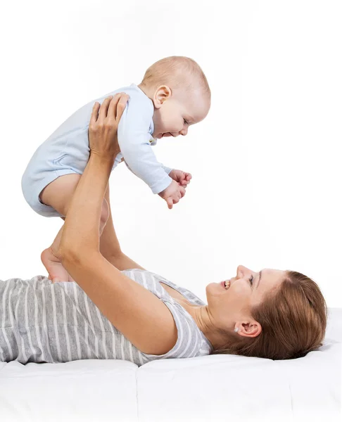 Szczęśliwa kobieta trzyma synka podczas leżenia na plecach — Zdjęcie stockowe