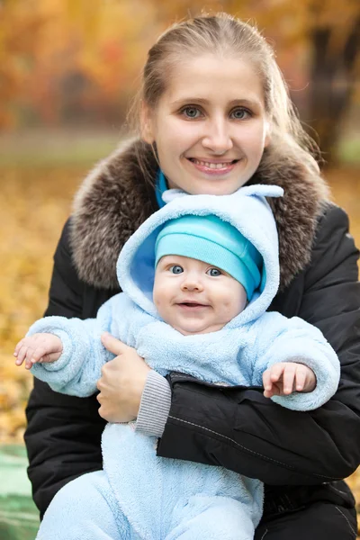 Ung kvinna med baby i höst park — Stockfoto