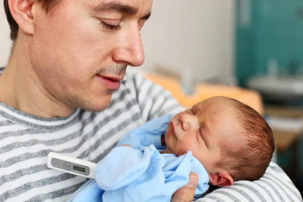 Отец и новорожденный сын с термометром — стоковое фото