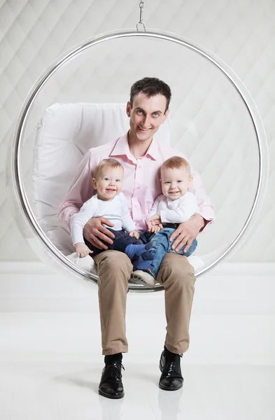 Father with two babies on swinging hanging chair — Stock Photo, Image