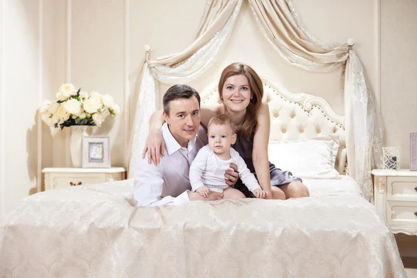 Junge glückliche Familie mit Baby im Bett — Stockfoto