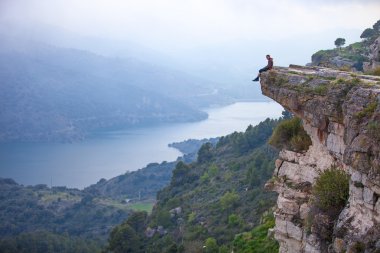 Young man sitting on edge of cliff