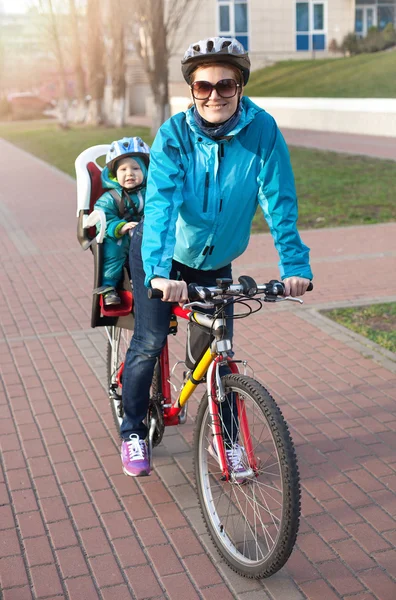 白种人年轻的女子在一辆自行车用后面的小儿子 — 图库照片
