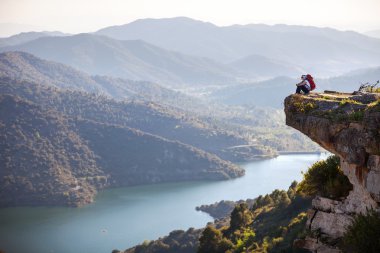 Cliff üzerinde oturan ve Vadi Manzaralı zevk kadın fiyatı