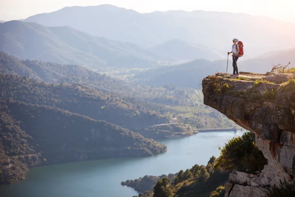 女性的徒步旅行者站在悬崖上，享受着山谷的景色 — 图库照片