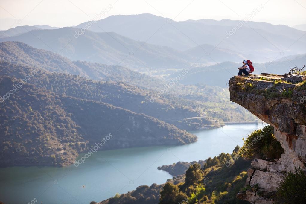 Female hiker sitting on cliff and enjoying valley view