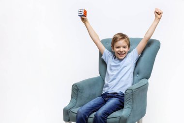 Kyiv, Ukrayna, 9 Ekim 2021: Rubik 'in küpünü tutan ve sevinçten kollarını kaldıran genç çocuk. Zihinsel bulmacayı çözdükten sonra mutluluğu ifade eden çocuk.