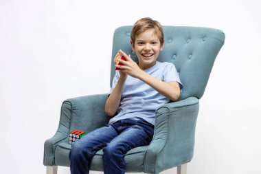 Kyiv, Ukrayna, 9 Ekim 2021, zihinsel bulmacaları çözen genç çocuk. Çocuk rahat koltukta otururken piramit bulmacası ve Rubik küpüyle oynuyor.