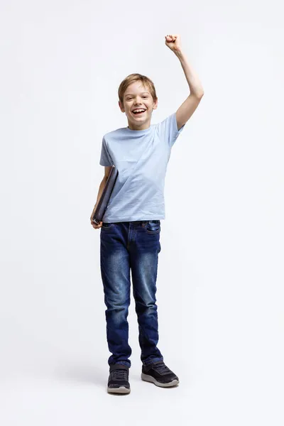Szczęśliwy Chłopiec Niosący Laptopa Pod Jednym Ramieniem Podnoszący Kolejnego Radością — Zdjęcie stockowe