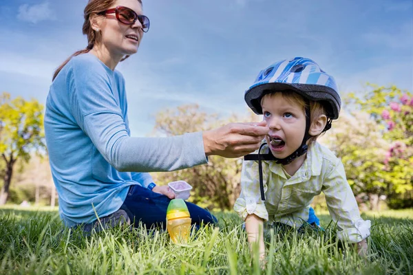 Mother Feeds Her Little Restless Son Outdoors Park — Stock Photo, Image