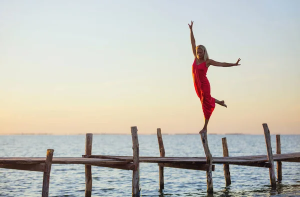 Beautiful Young Woman Red Dress Stands One Leg Jetty Sunset — Foto de Stock