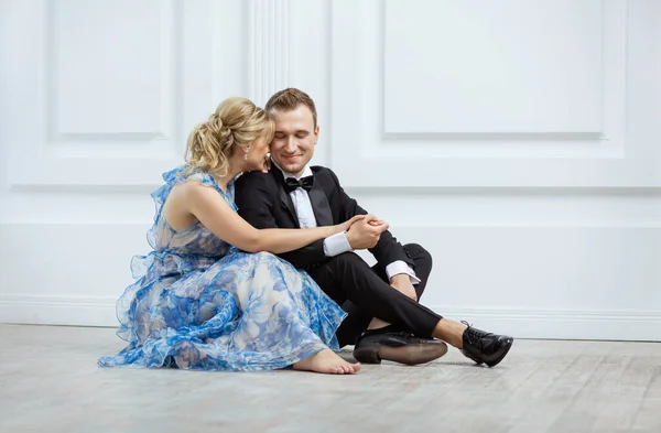 Young couple in luxury fashionable clothes sitting on floor and hugging