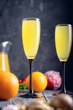 Karanlık bir arka plan, iki bardak şampanya ve portakal suyu. Mimosa Kokteyli