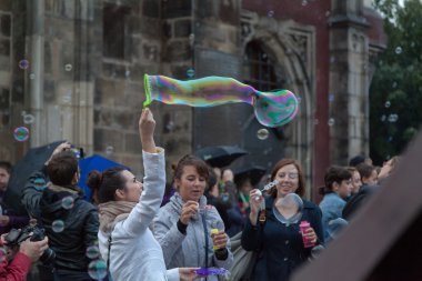 sokakta sabun köpüğü ile oynayan kızlar.