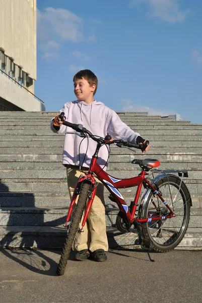 O menino segura sua bicicleta vermelha — Fotografia de Stock